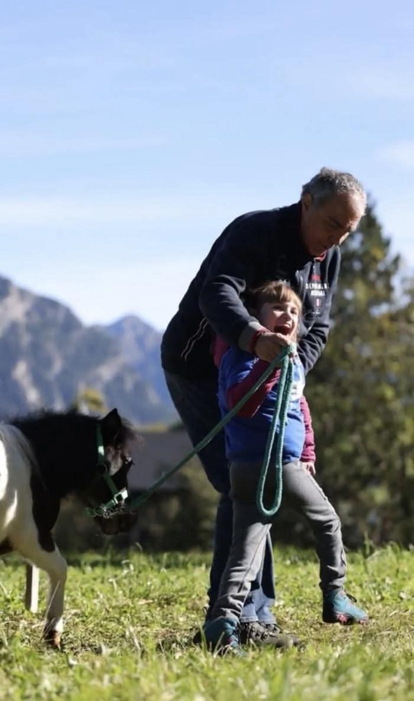 Ely nel prato con un mini pony, montagne sullo sfondo